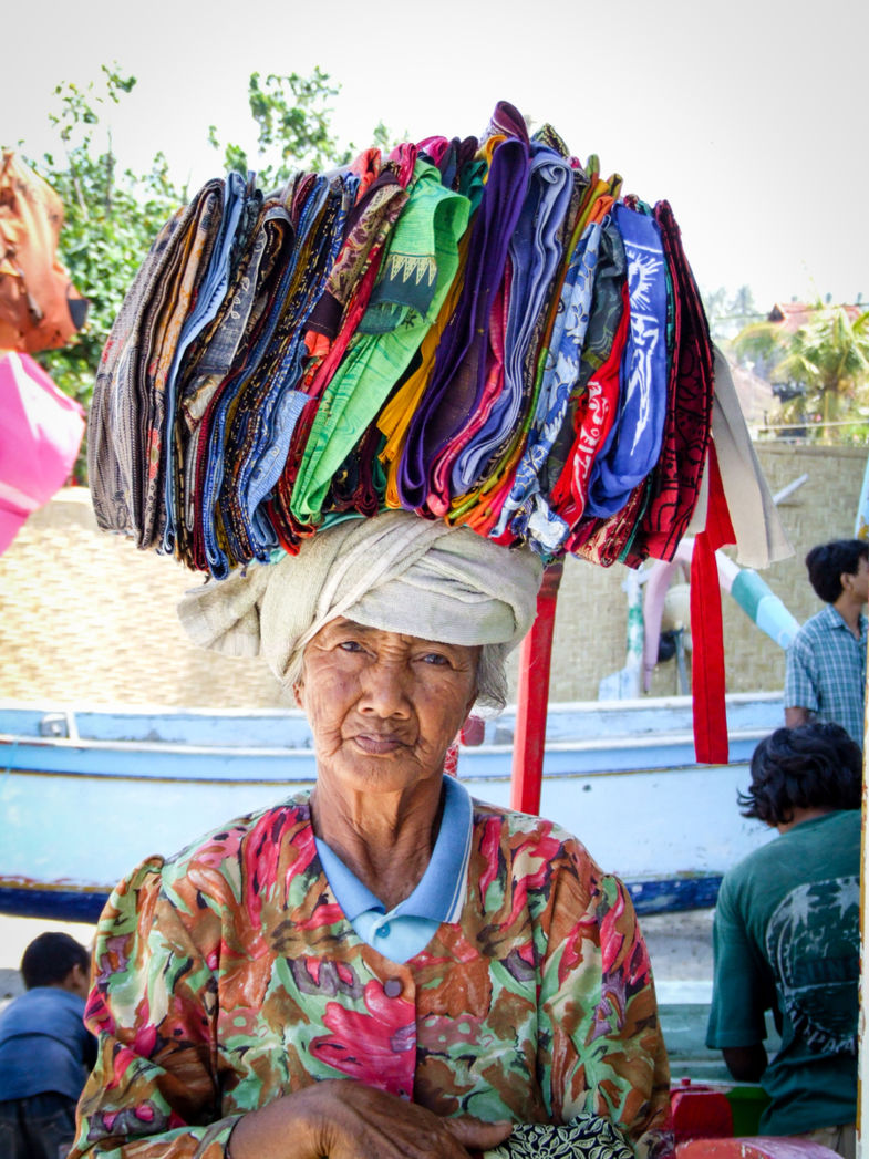 Lieve Balinese oude vrouw verkoopt batik-doeken.
