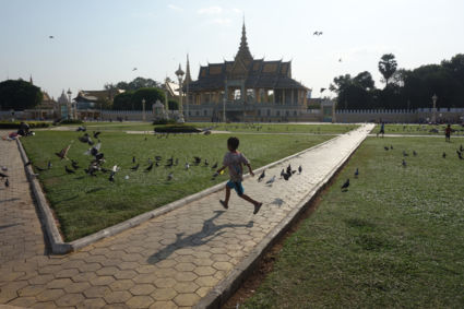 Vliegend en spelend kind in lijn met de vogels in Phnom Penh